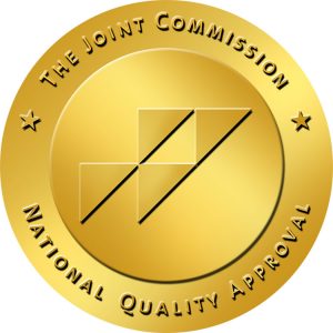 A gold circular badge with black diagonal lines and the text 